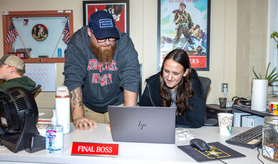 A man and woman look at a laptop together while smiling