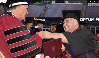 Ben Sangiolo, class of 2020 and graduate class of 2021, giving BSU president Fred Clark a fist bump at Commencement
