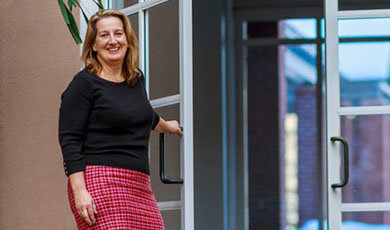 Michelle O'Connor, class of 1988, smiling and opening a door
