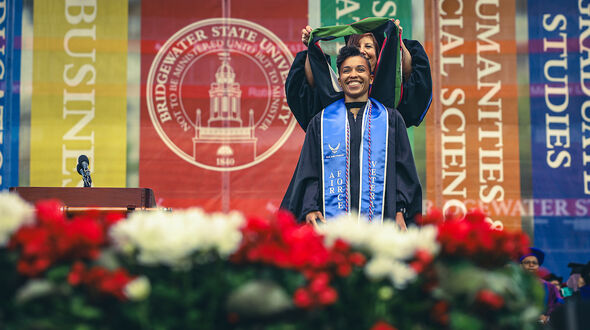 a graduate student receives her hood at graduate commencement