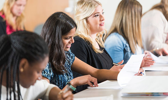 BSU graduate students sitting at a table in class taking notes and listening to the professor
