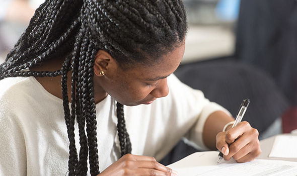 a student leans over a desk writing