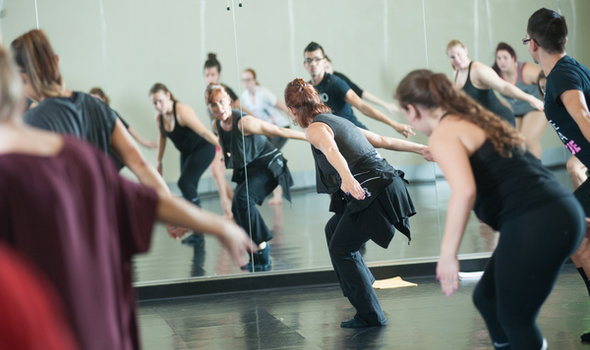 Professor Jodi Weber leading a modern dance class as they all dance facing a mirror