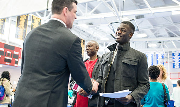 BSU student smiles and shakes hands with a man in a business suit at BSU Business job fair
