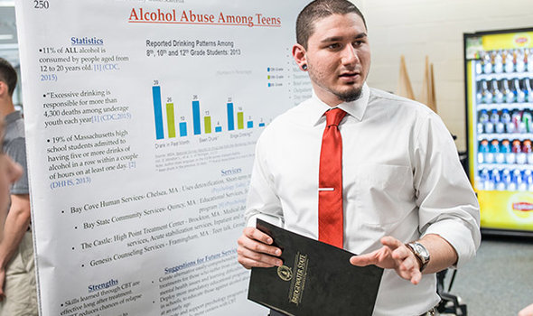 BSU student dressed in button down white shirt with red tie presenting his research