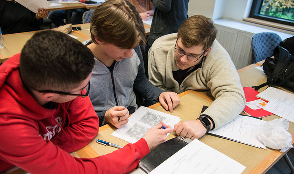 Three students working out a problem at their desk in a Math and Politics class
