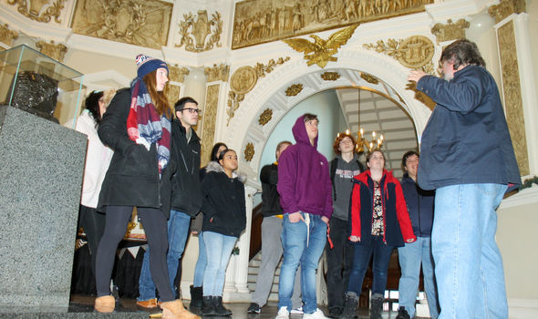 Dr. James Hayes-Bohanan and his students stand inside an ornate hall