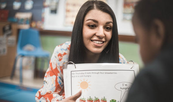 BSU student Taylor Alfonse smiling while showing a large book page to a preschool student