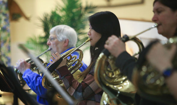 A student plays the French horn in a music ensemble