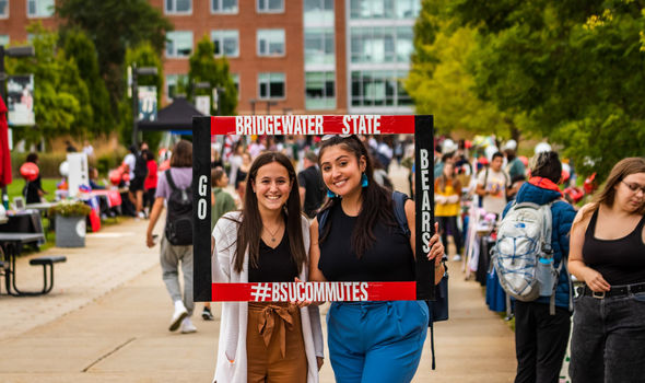 At BSU Involvement Fair, 2 students look out from a frame that says #BSUCOMMUTES