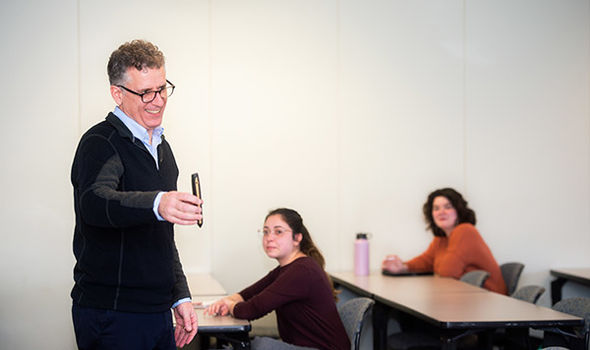 Professor James Feeney holding out a teaching aid while teaching a class