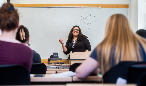 Dr. Fernanda Ferreira teaching standing in front of a whiteboard with students at their desks listening
