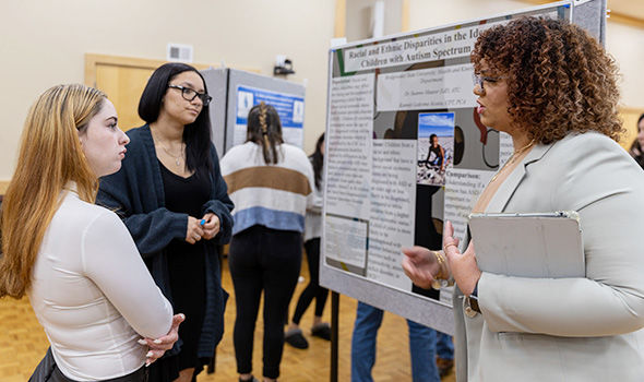 A student presents research to two other students at the STARS symposium