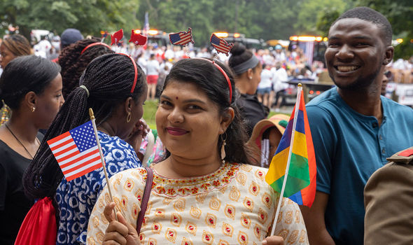 Two Mandela Washington Fellows smiling for the camera at the Bridgewater 4th of July parade; one holds the flags of the U.S. and Mauritius