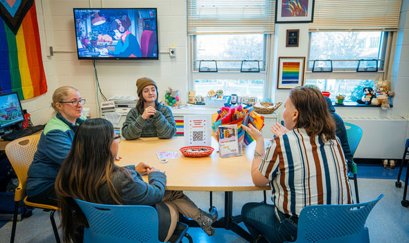 Pride Center director and students sit around a table in the center talking