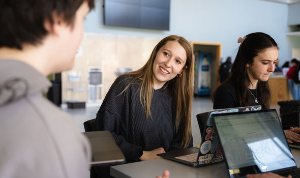 Four BSU students work and talk together at open laptops