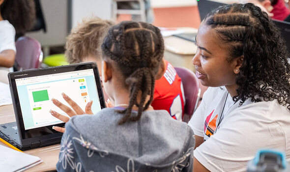 A BSU student teacher helps an elementary school student with work on a laptop