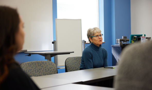 Dr. Susan Eliason sitting at a classroom table talking to students
