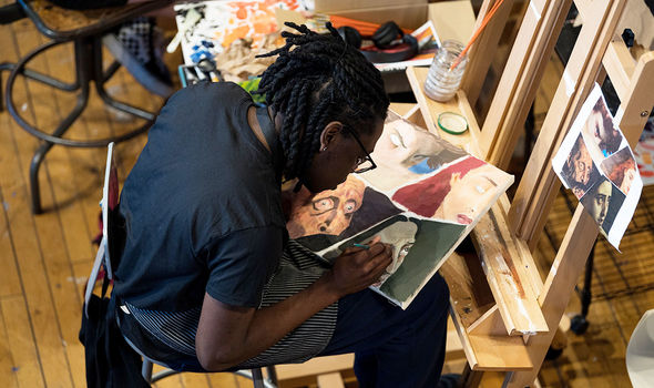 A student works on a painting in the art studio