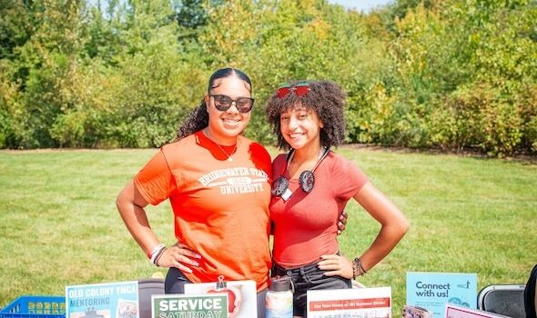 Two female students standing in front of a table smiling