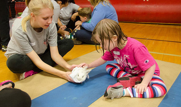 BSU student holding a bunny while a child pets the bunny