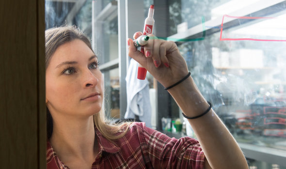 female student mapping with markers on clear glass
