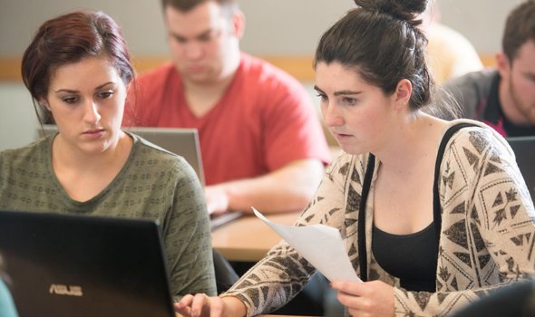 students working on laptop in class