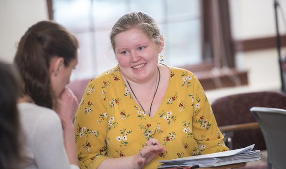 A student smiling in history class talking to another student