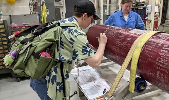 Abby Brown signs name on exterior of a red rocket