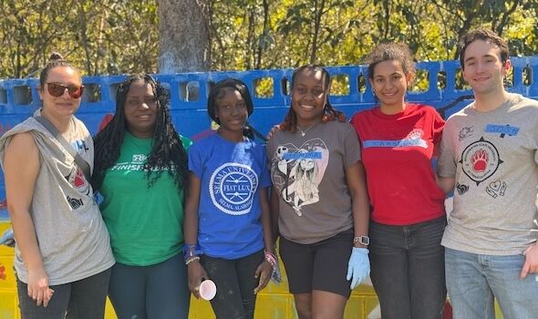 5 students stand with Dr. Hannah Stohry at a local service site in Selma, AL