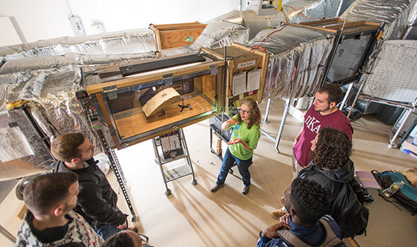 a BSU professor teaching a class in front of the BSU wind tunnel