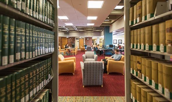 A student is seen through the stacks at the Library studying