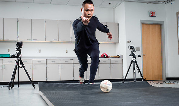 a student &quot;bowling&quot; a ball in lab while being recorded with small balls attached to his clothing