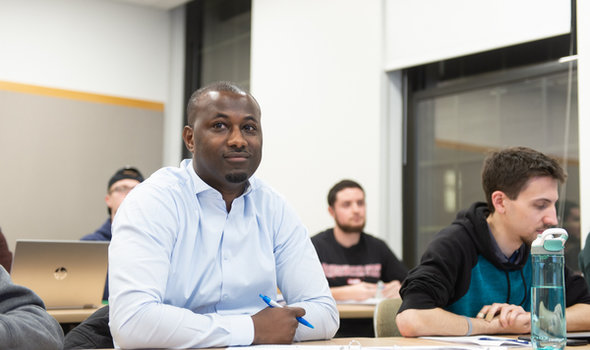 4 students sitting at desks in in a graduate class