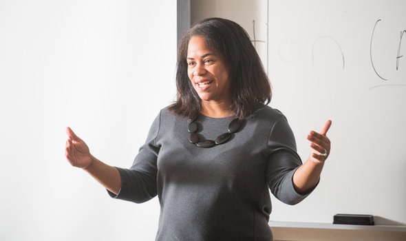 Dr. Mia Ortiz smiling and speaking to a class in front of a white board