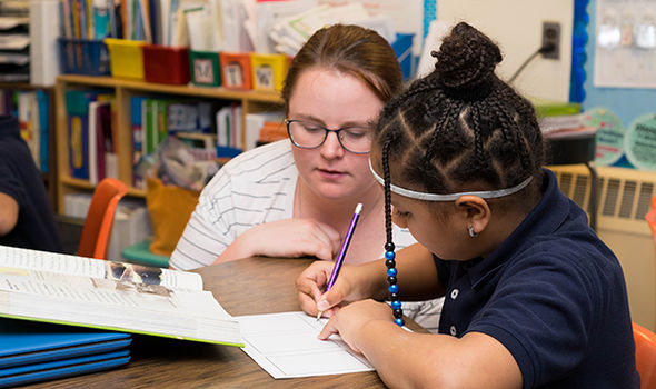 a BSU student helping a young student with a reading and writing activity