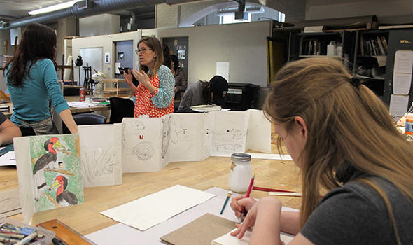 BSU student making a book while Professor Leigh Craven talks with another student