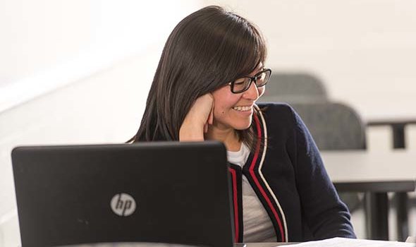 A student sits in front of her laptop in class