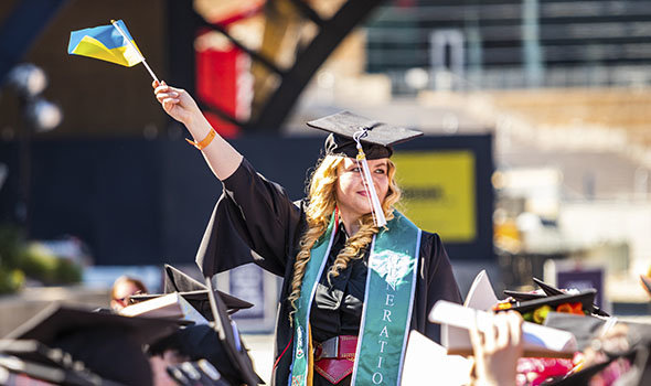 A graduating student from Ukraine waving the Ukrainian flag at commencement
