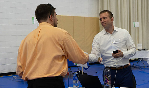 Two men shaking hands over a table at a BSU job and internship fair