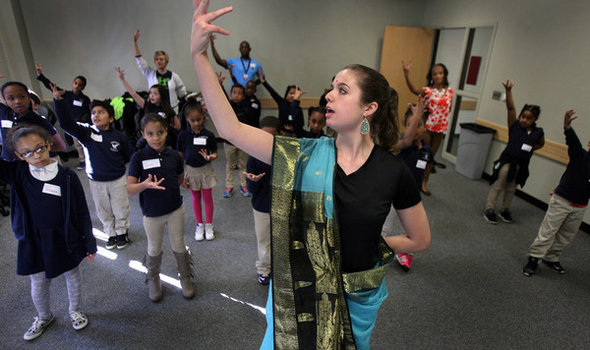 a BSU student teaching elementary school age children how to do a dance from India