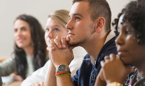 4 BSU students sit at a classroom table in Management class paying positive attention to the professor's lesson