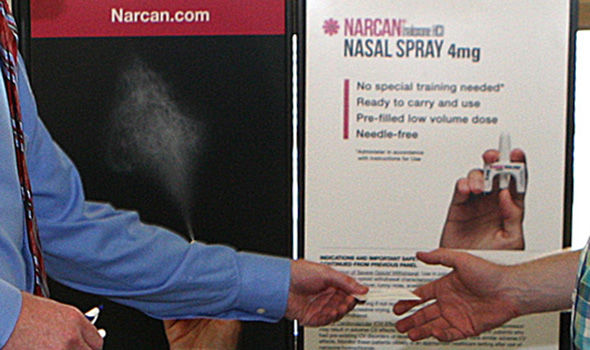 Someone hands another person a card in front of an information display about Narcan