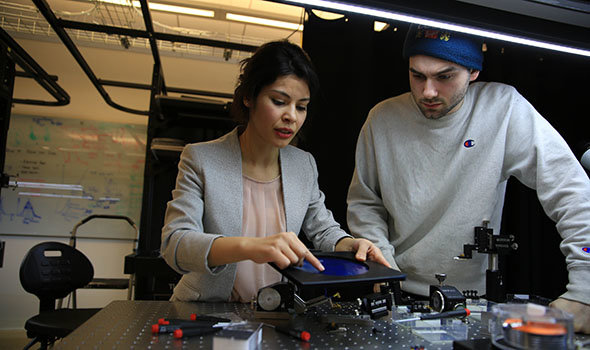 Two photonics students looking over equipment in the lab