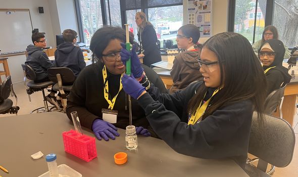 A class of students working on an experiment in the lab, piping liquid into a vial