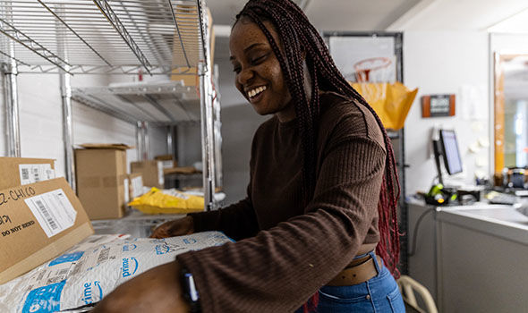 A student employee sorting packages in the university mailroom