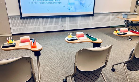 A classroom with individual desks, each set up with a science experiment kit