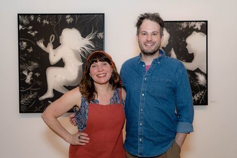 A man and woman stand next to each other smiling