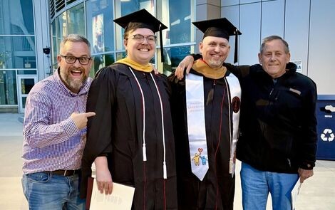 Four men stand smiling