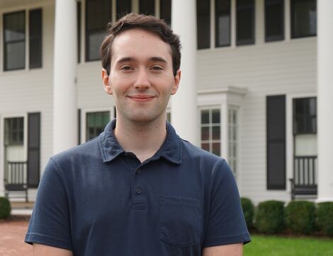 A man wearing a blue shirt smiles at the camera 